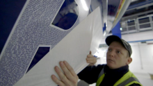 Worker placing names on the side of a lifeboat